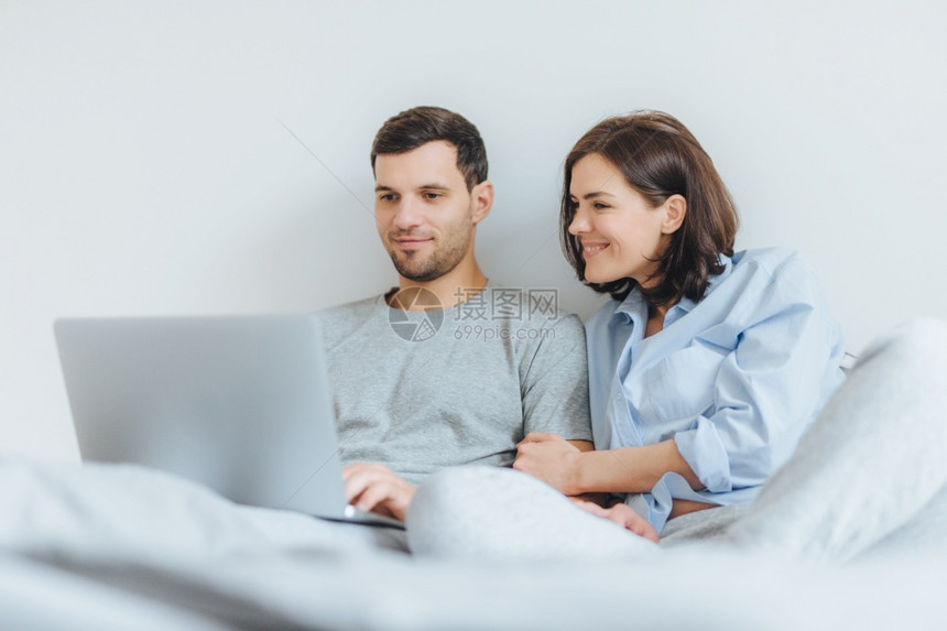爱的男女一起快乐在笔记本电脑上看卧室的影享受在一起和免费的互联网连接图片