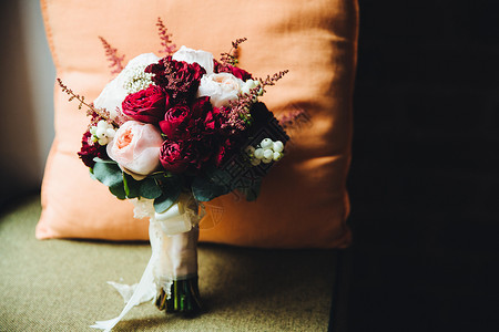 在室内拍摄美丽的红花和白玫瑰与丝带站在一起坐椅子上与枕头对着图片