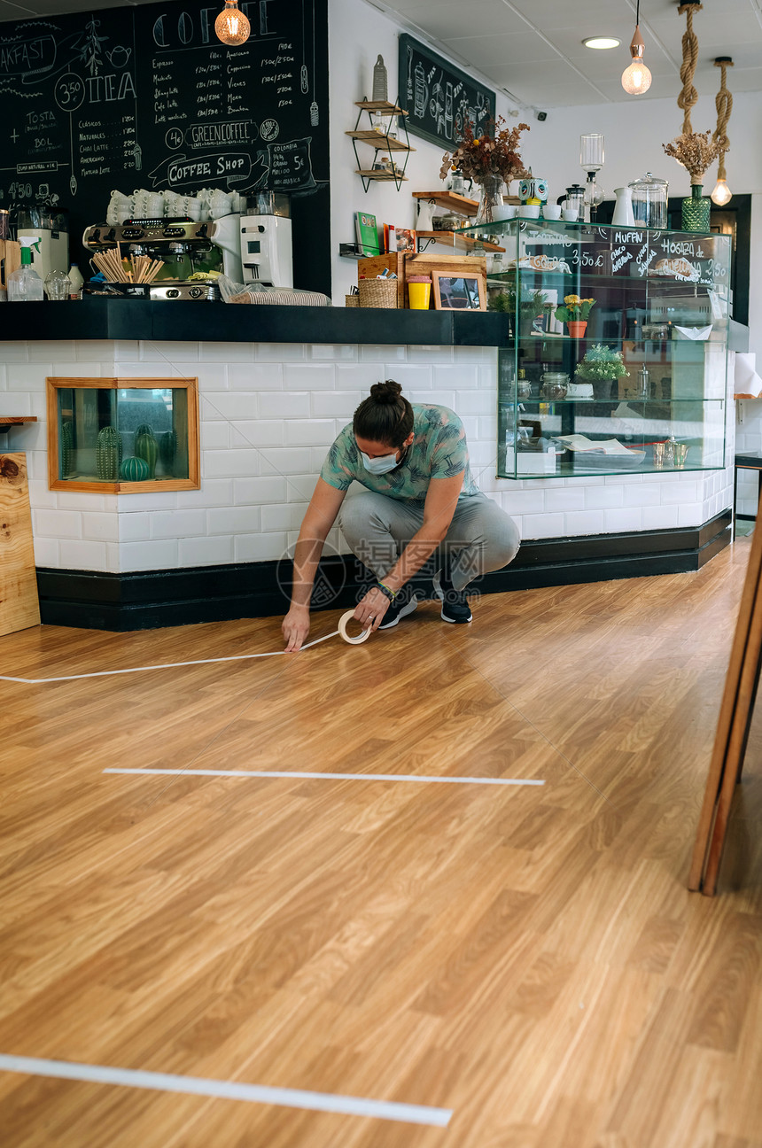 咖啡店工人使用地板标记以保持社会距离图片