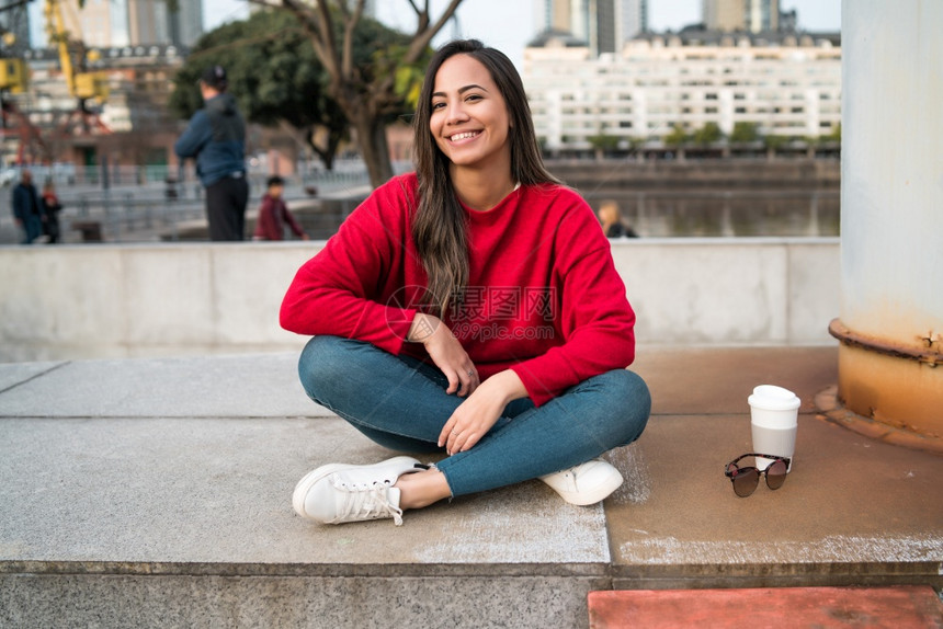 坐在户外喝着咖啡的拉丁女青年肖像城市概念图片