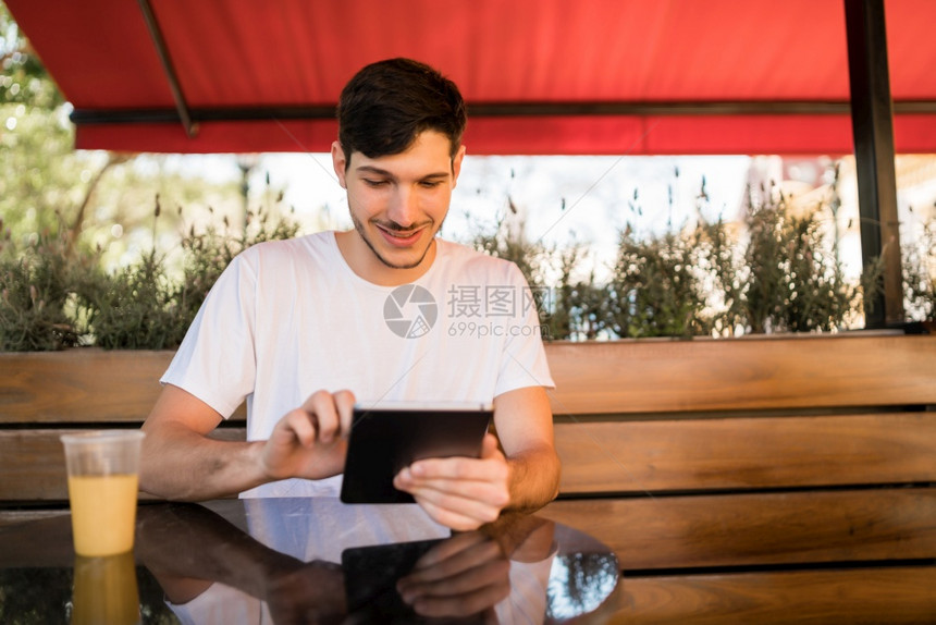 年轻人坐在咖啡店时使用数码平板电脑的肖像图片