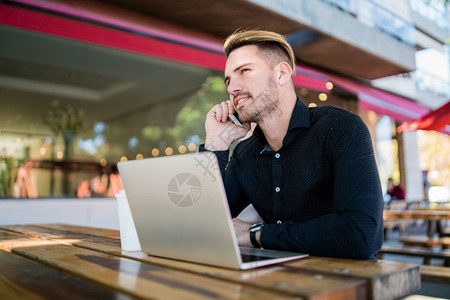 年轻商人在咖啡店工作时在笔记本电脑上讲话图片