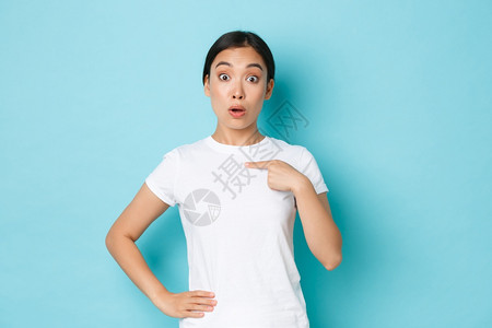 穿着白色t恤的年轻女孩惊讶地对着自己指不知所措的表达方式被选中或点名图片