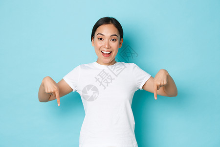 去中心化云计算身穿白色t恤的快乐年轻女身穿白色t恤手指向下微笑着兴奋的看自己背景