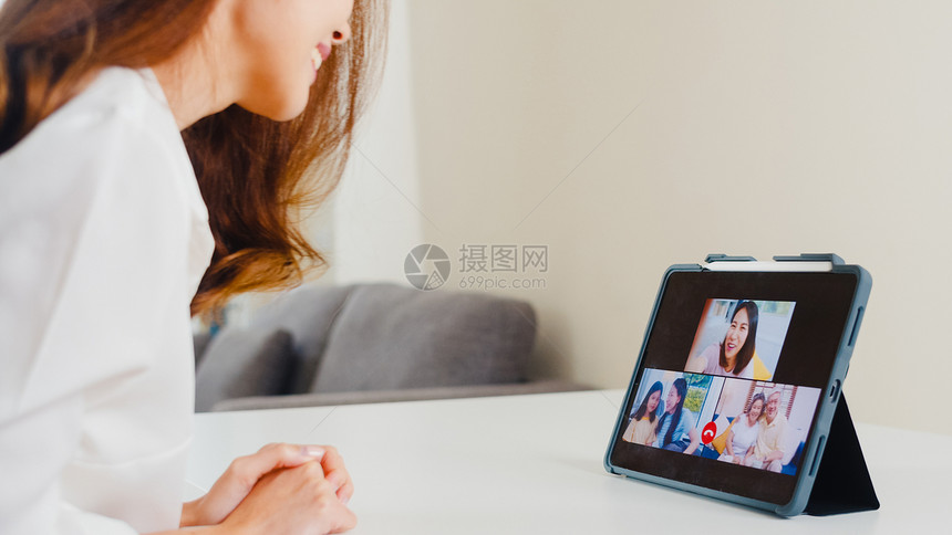 在客厅工作时使用平板视频电话与家人交谈图片