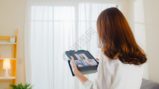 在客厅工作时使用平板视频电话与家人交谈图片