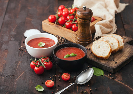 瓷碗盘加勺子胡椒和木板上的厨房布加盒生番茄和面包高清图片