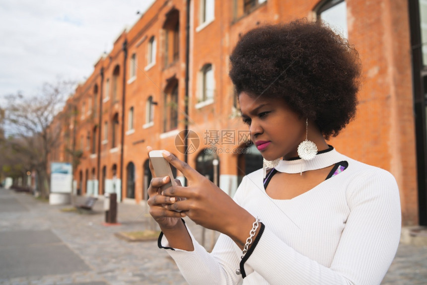 使用手机在街上露天拍摄的美国拉丁女画像图片