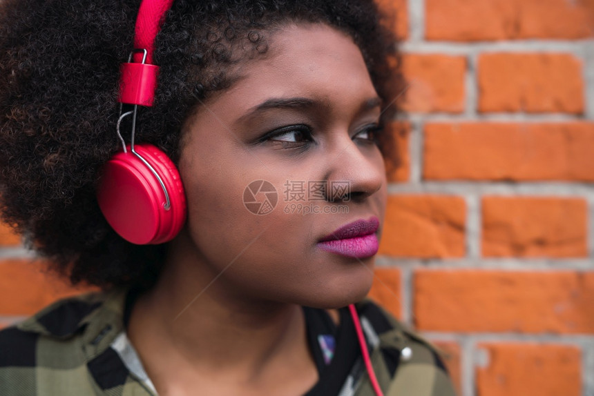 年轻美国拉丁女人在街上用耳机收听音乐的肖像图片