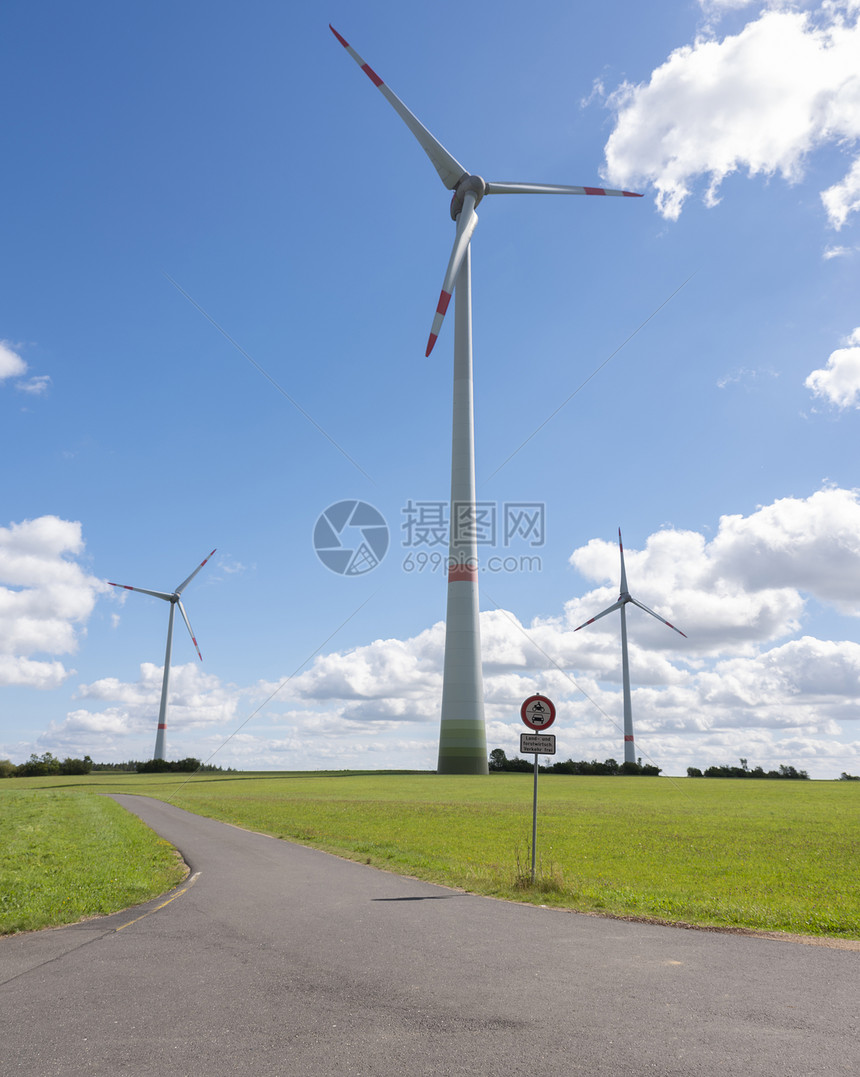 在阳光明媚的夏日以绿草蓝天和白云为绿草用德国菜叶中的风涡轮机图片