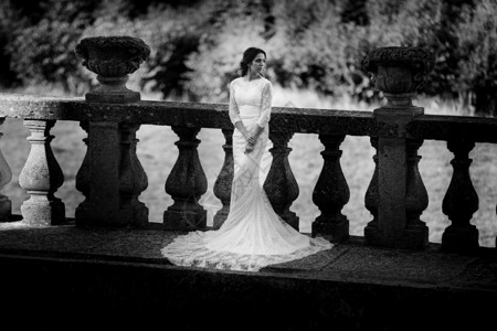 身着豪华礼服的美丽新娘站在大阳台上黑白照片背景图片