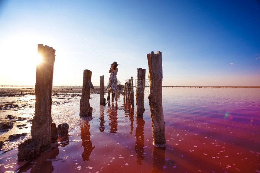 女孩在日落时著名的粉红盐湖上表演在中反射图片