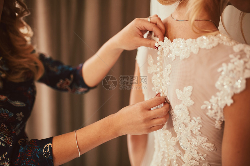 伴娘在婚礼前帮新准备结婚日的新娘伴在婚礼前帮助缝合服豪华新娘婚纱关闭礼伴娘为新准备结婚日的新娘图片