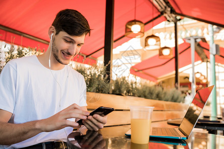 年轻人在咖啡店户外活动时使用手机的肖像图片