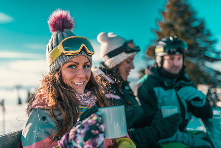 令人愉快的喝朋友们在山上享受冬日在户外喝咖啡或茶背景
