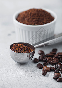 白陶瓷碗中的咖啡粉和浅色桌底的钢制咖啡团背景图片