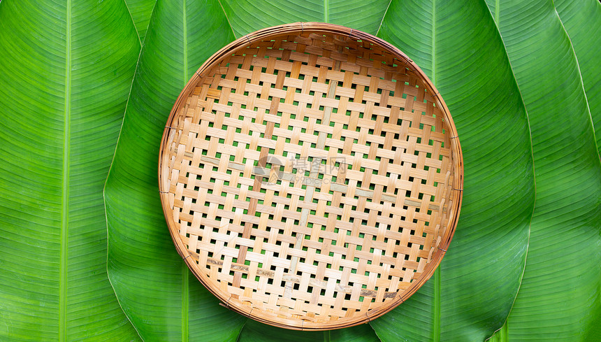 香蕉叶背景上的空木竹子篮图片