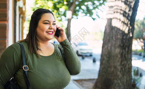 年轻又大的女人在街边户外电话交谈时微笑的肖像图片