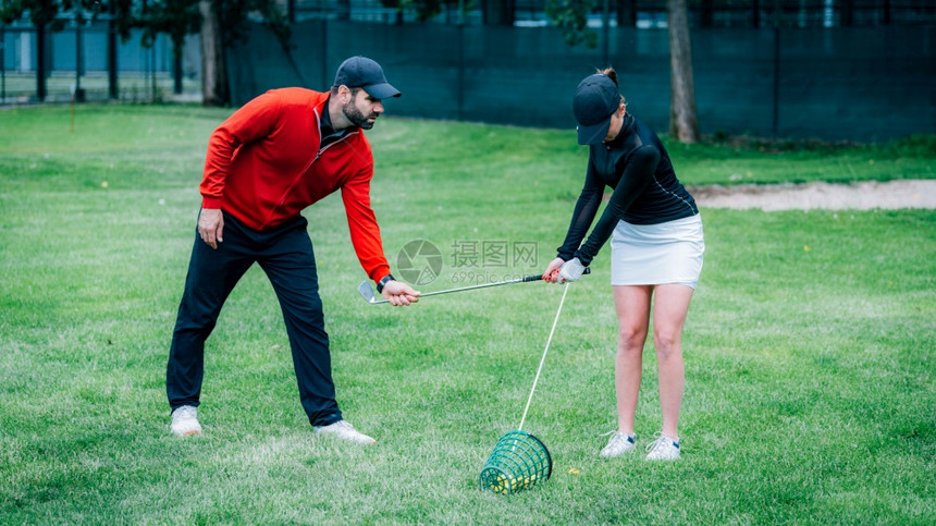 与年轻女一起工作改善摇摆状况的高尔夫教练图片