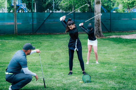 在高尔夫球场上与两名年轻女士一起工作的高尔夫教练图片