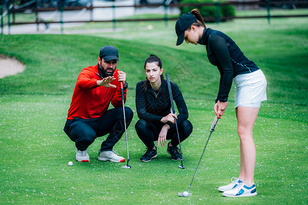两个年轻女高尔夫运动员练习与高尔夫教一起打高尔夫图片