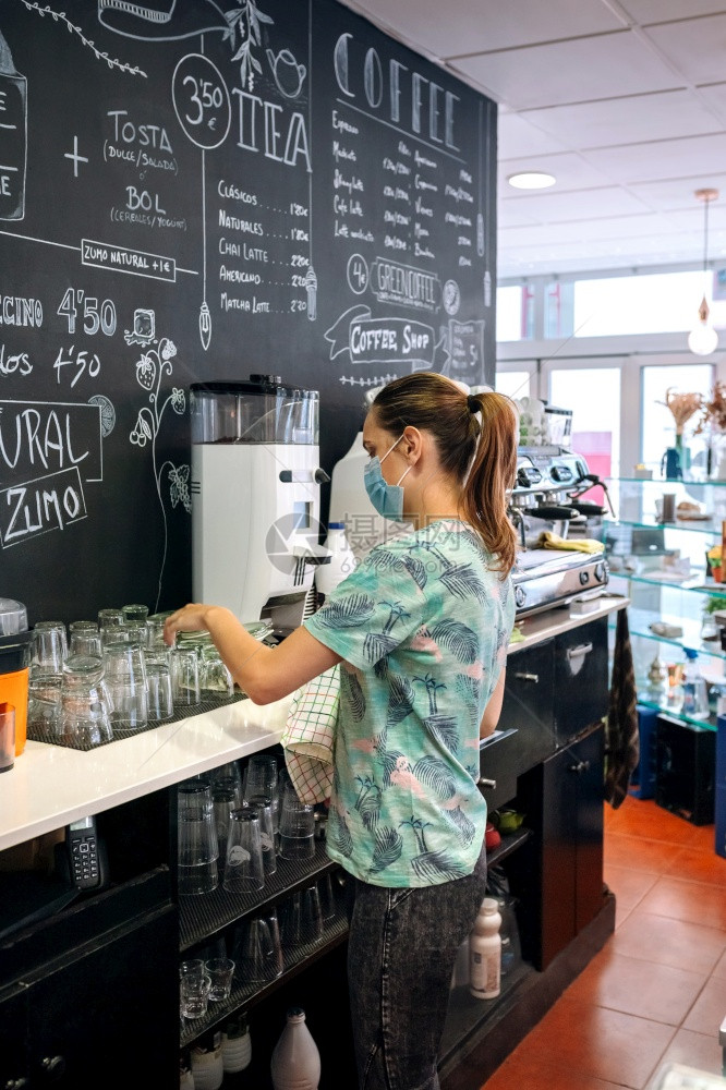 咖啡店内戴面罩清洁眼镜的年轻女服务员戴面罩清洁眼镜的女服务员图片