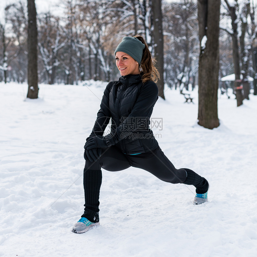 冬季女运动员在公园里微笑着运动拉伸图片