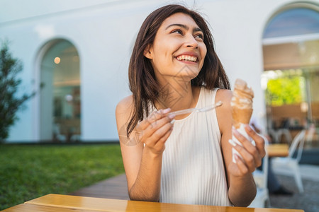 年轻女在户外吃冰淇淋时享受阳光的天气图片