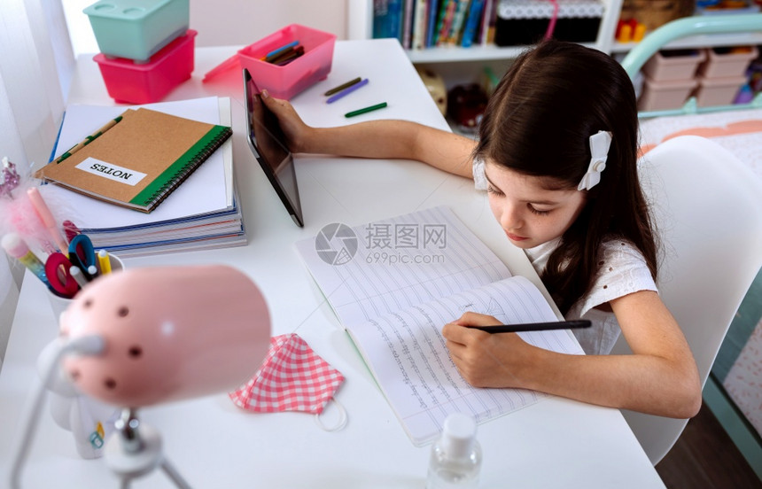 在家里学习用平板和面罩在桌子上学习的小女孩在家里学习用平板和面罩在桌子上学习的女孩图片