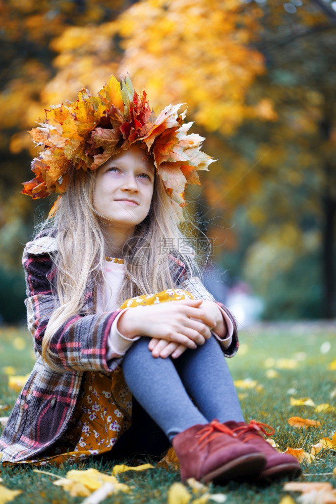 在公园玩乐的年轻女孩带着黄色的金树叶Diadem图片
