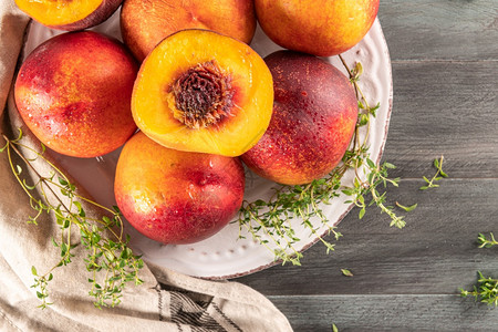 油桃熟了熟的桃子在木板上背景的子上用百叶树作为盘子放在木板上背景背景