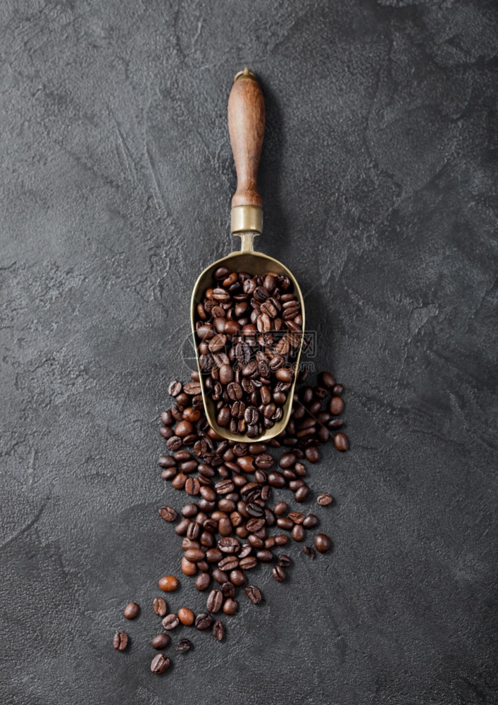 黑色背景的旧钢勺中新鲜生有机咖啡豆顶部视图图片