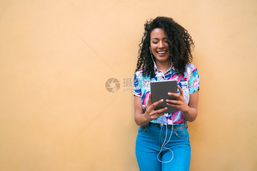 年轻快乐的美国拉丁女人肖像在她数字平板电脑技术概念上聆听音乐图片