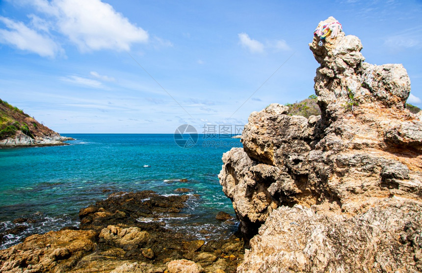 蓝色天空下的绿海白云和岩石悬崖位于普吉的亚努伊海滩图片