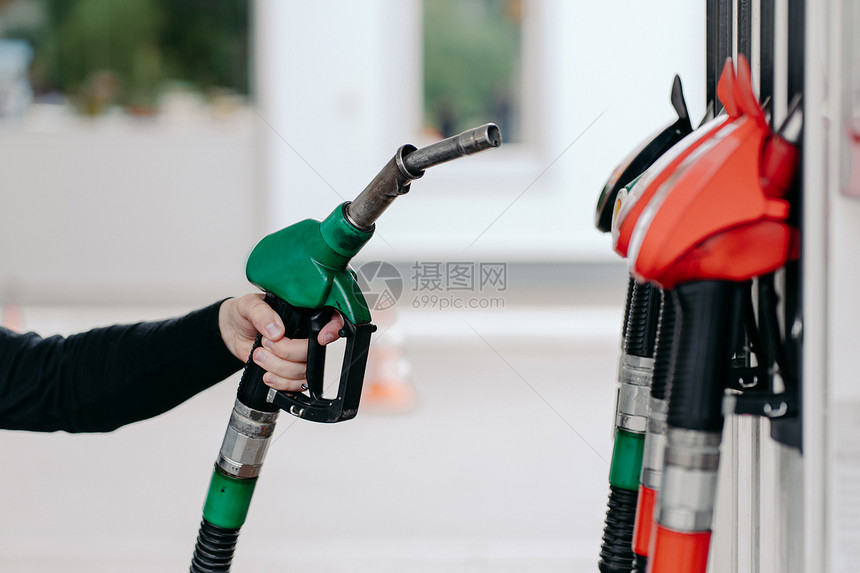 在加油站使用燃料喷嘴的男子手、关闭加油柴和煤气。图片
