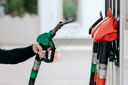 气体行业在加油站使用燃料喷嘴的男子手、关闭加油柴和煤气。背景