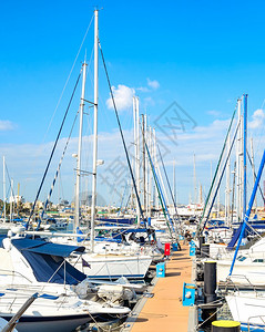 在码头停泊的白色游艇和机动停靠在明阳光拉纳卡锡普勒斯的码头图片
