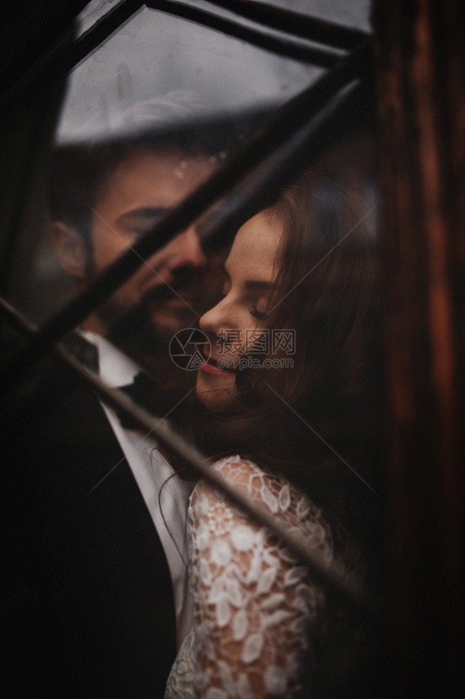年轻时尚的新婚夫妇被拥抱在老旧的木制门后面婚礼当天年轻时尚的新婚夫妇被拥抱在老的木制门后面图片