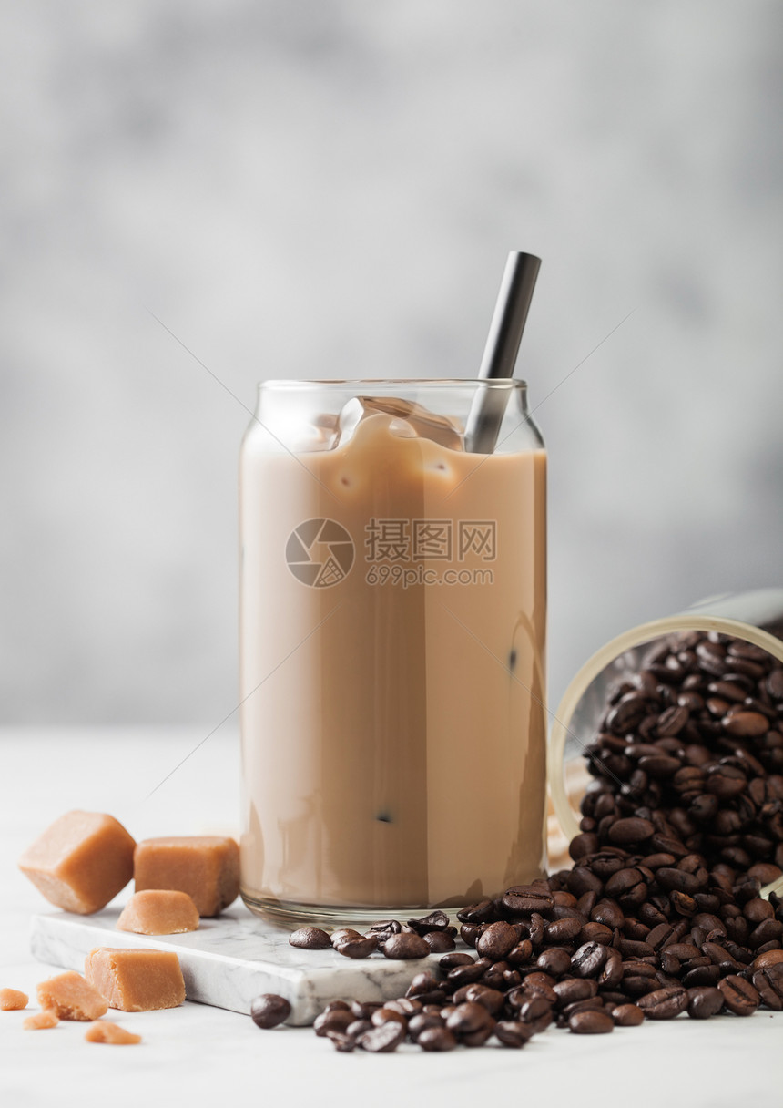 冷冰咖啡牛奶装在玻璃里加一罐新鲜咖啡豆和浅桌底的咸焦糖图片