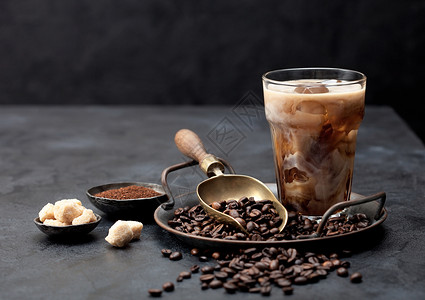 咖啡豆盘上加牛奶的冰黑咖啡和豆盘上加牛奶的冰黑咖啡甘蔗糖和黑底土咖啡以及豆粉文本空间背景图片