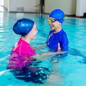 游泳学校可爱的小男孩和游泳教练玩得开心图片