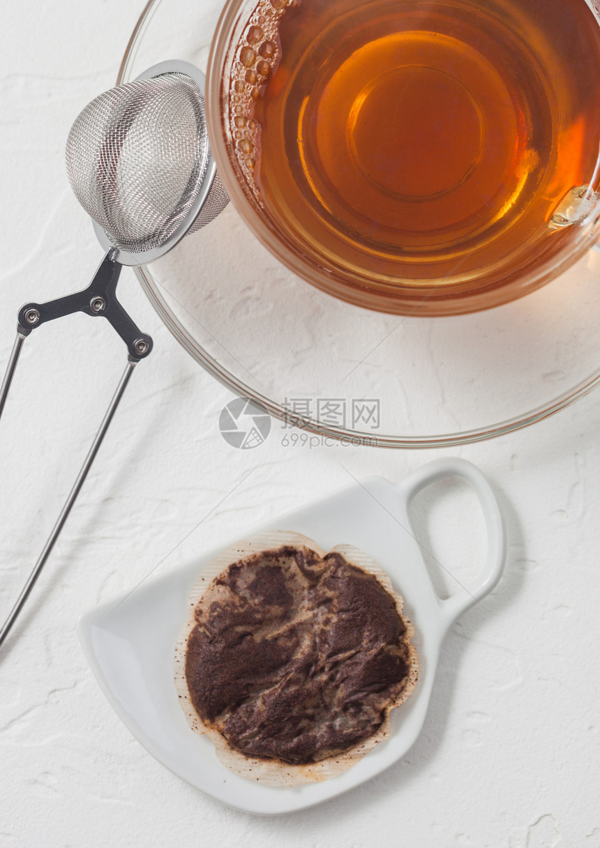 陶瓷板上用过茶包面装有杯和白色背景的教练喷雾器图片