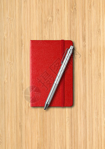 红色关闭笔记本用木制背景上隔离的模型红色关闭笔记本用木制背景上的笔图片