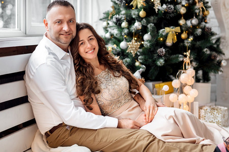 一对夫妻坐在圣诞树旁拥抱图片