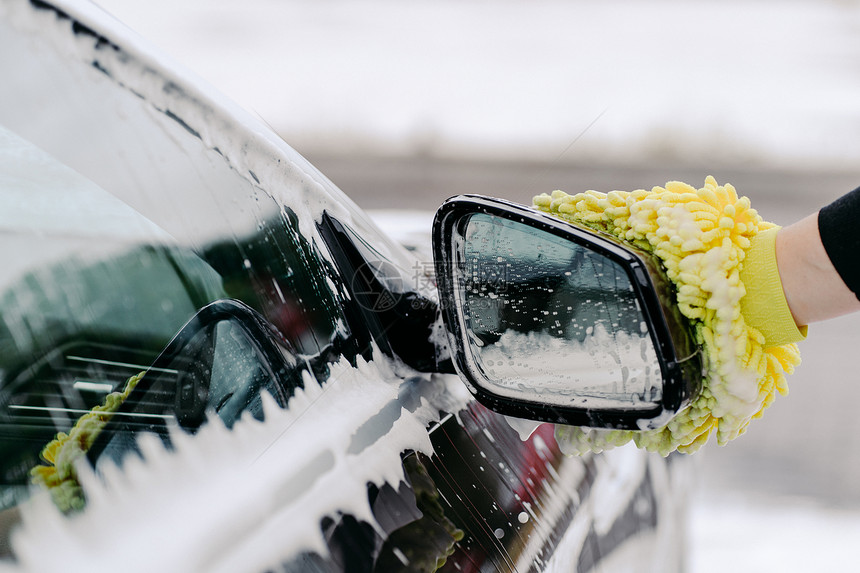 持有黄色海绵洗车侧窗的男子手持黄海绵洗车侧窗在清洁服务上加泡沫汽车清洁图片