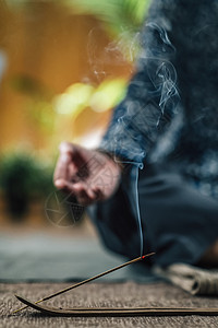 德拉威人有选择的焦点放在烧香棍和烟雾上女在背景中冥想祈祷时握手放胸前家里用香棍冥想手指在gyanmudr智慧的象征背景