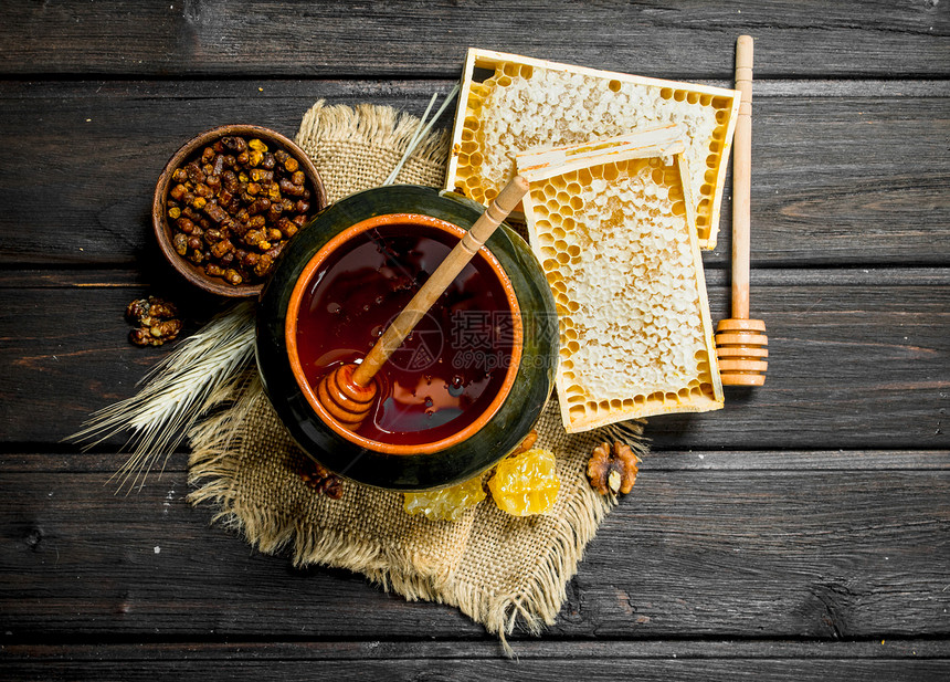 纯天然蜂蜜在锅中勺子木制背景上天然蜂蜜在锅中勺子图片