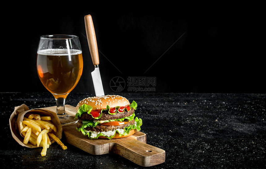 汉堡包用刀子薯条啤酒在杯子里黑色生锈背景啤酒在杯子里图片