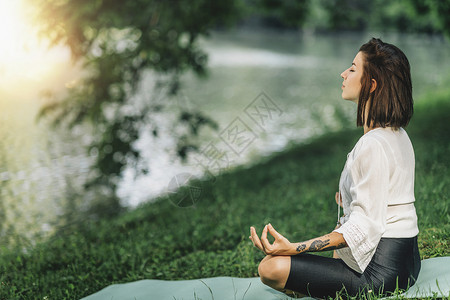 年轻女在自然界水附近进行冥想图片