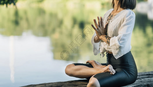 在湖边冥想的用手坐在莲珠上着祈祷姿势静默地坐在湖边图片